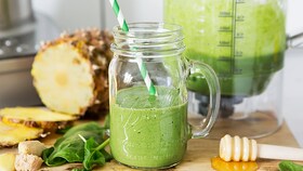 Čerstvě připravený nápoj smoothie z listové zeleniny ve skleněné nádobě s brčkem