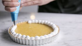 Pekař nanášející hladké pusinkové těsto na citronový pusinkový koláč