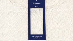Bílý vlněný svetr se štítkem Electrolux s pokyny k dokonalé péči