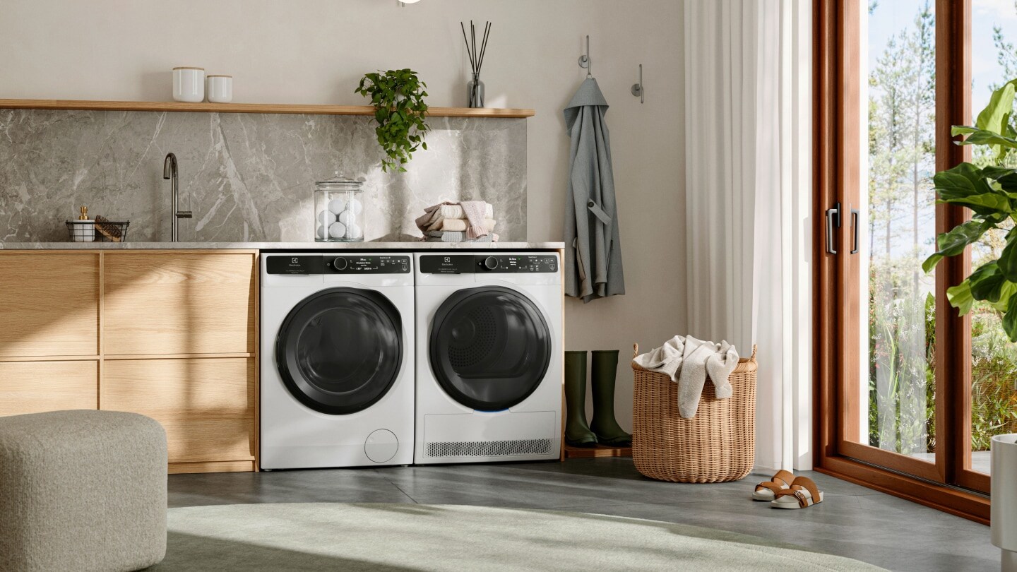 Prádelna s pračkou a sušičkou Electrolux umístěnými vedle sebe pod pultem.