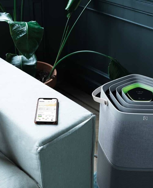 A smartphone on a couch next to a Air purifier