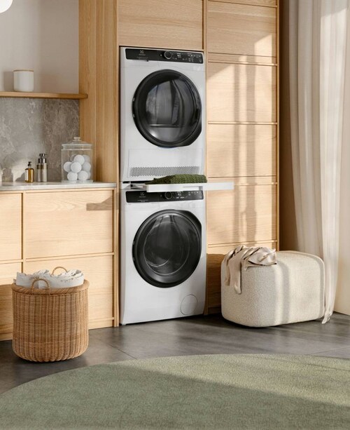 Pračka a sušička Electrolux jsou postavené na sobě v prosluněné místnosti.