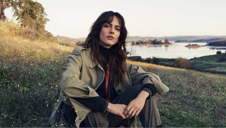 Žena sedící na trávě v přírodě.