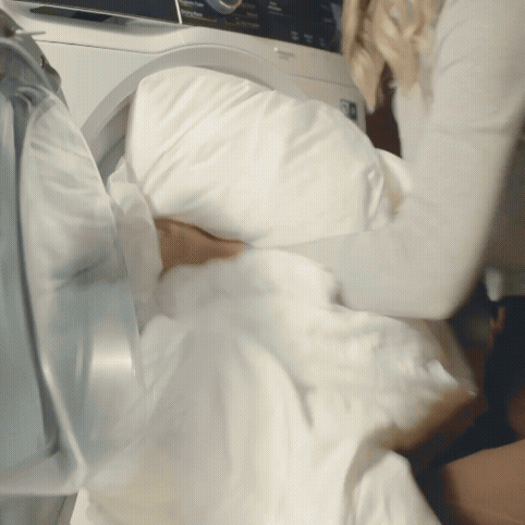 GIF, kde žena pere a suší bílou přikrývku.