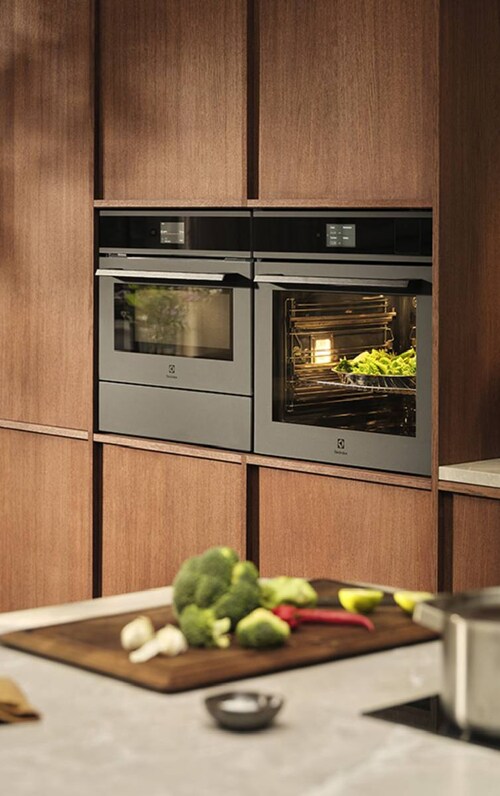 Vestavěné dvojité trouby v dřevěných kuchyňských skříňkách.