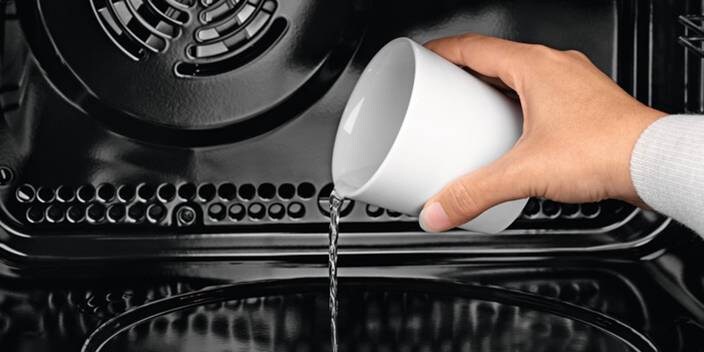 Osoba lijící vodu do vnitřku trouby